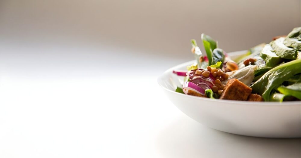 白いボウルに盛り付けられたアボカドや豆類のサラダ。日本人の腸活や更年期のお腹を整える習慣をイメージした清潔感のある写真