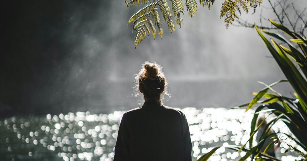 水辺を見つめながら静かに立つ女性